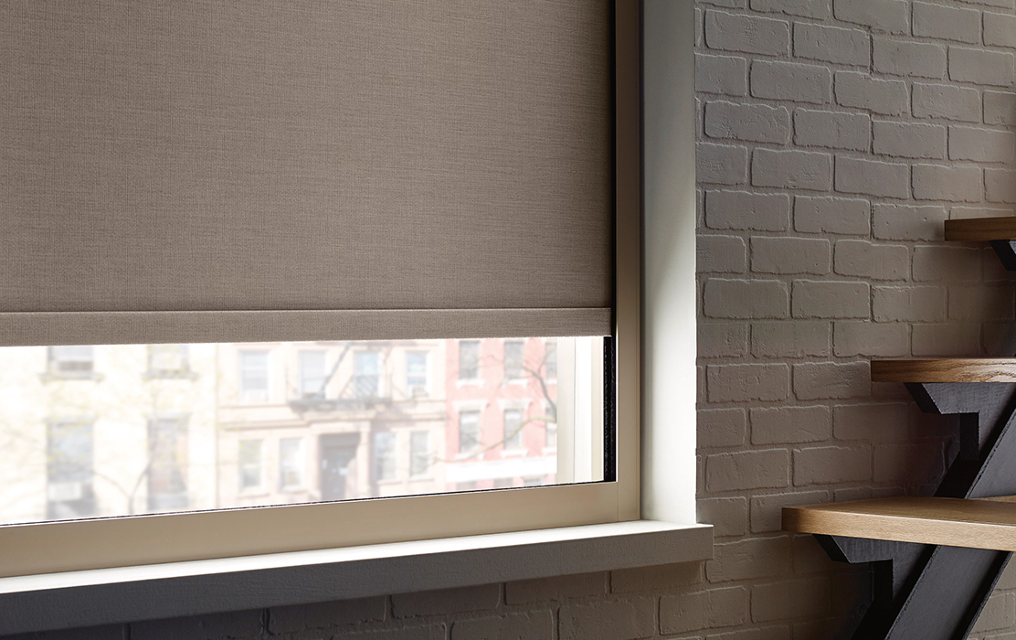 A stylish office with a modern window treatment. The designer roller shades are pulled down to provide complete room darkening, ideal for focused work or presentations.